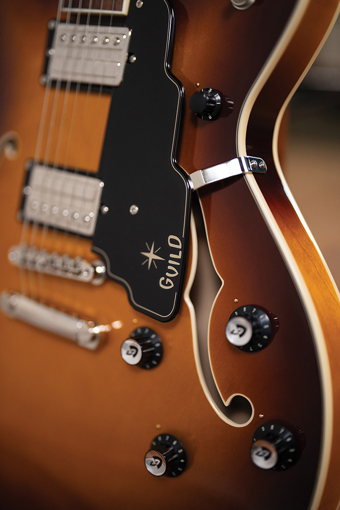 Close-up of the upper cutaway horn on a Starfire Deluxe DC Sweet Tea, showing the pickguard with Guild logo, tailpiece, and control knobs.