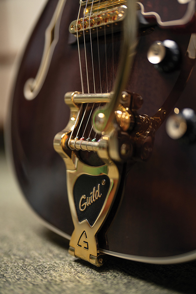 Close-up of the gold Guild Vibrato tailpiece on a Starfire Custom DC GVT GH, showing the engraved Guild script.