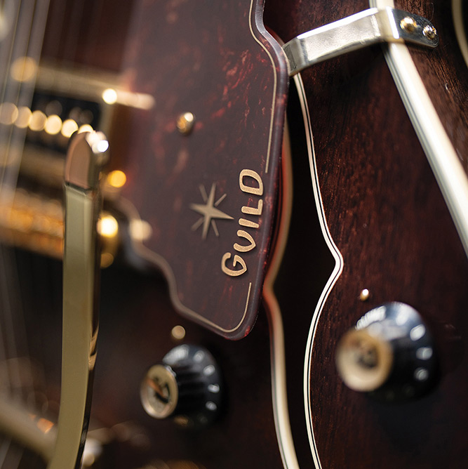 Close-up of the lower bout on a Starfire Custom DC GVT GH, showing the Guild starburst logo, vibrato arm, and control knob.
