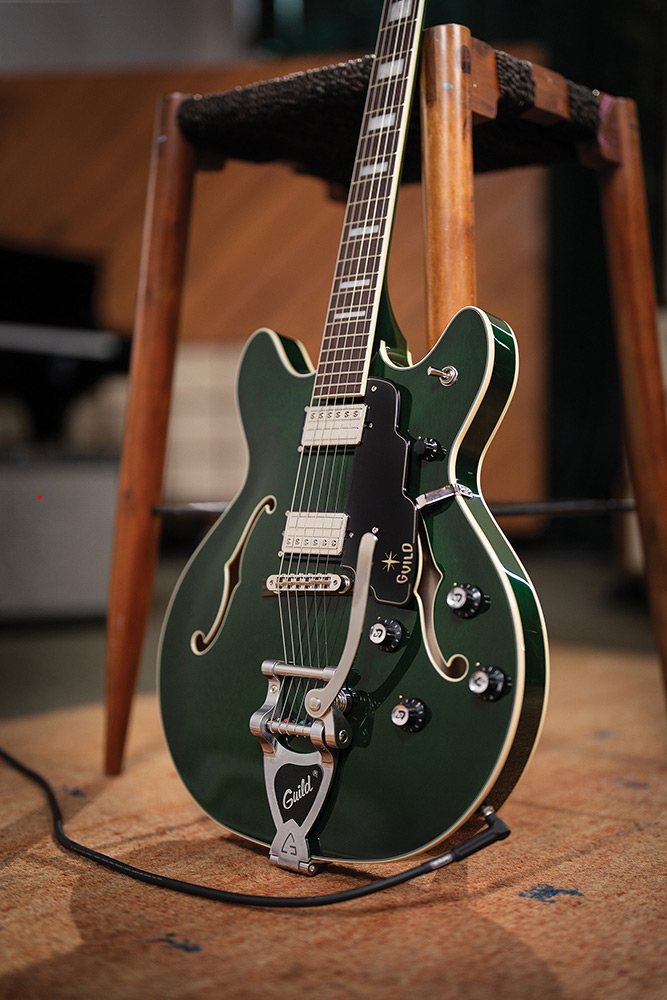 Full view of a Starfire Deluxe DC GVT Emerald Green leaning against a stool, showing the double-cutaway body, pickguard, and pickups.
