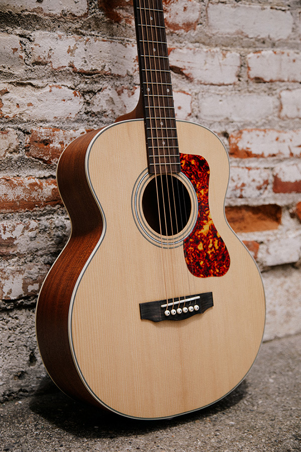 Close-up of Jumbo Junior Mahogany body in front of a brick wall