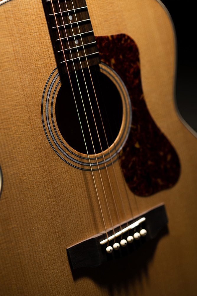 Close-up of F-240E Natural body showing pickguard, soundhole, and bridge