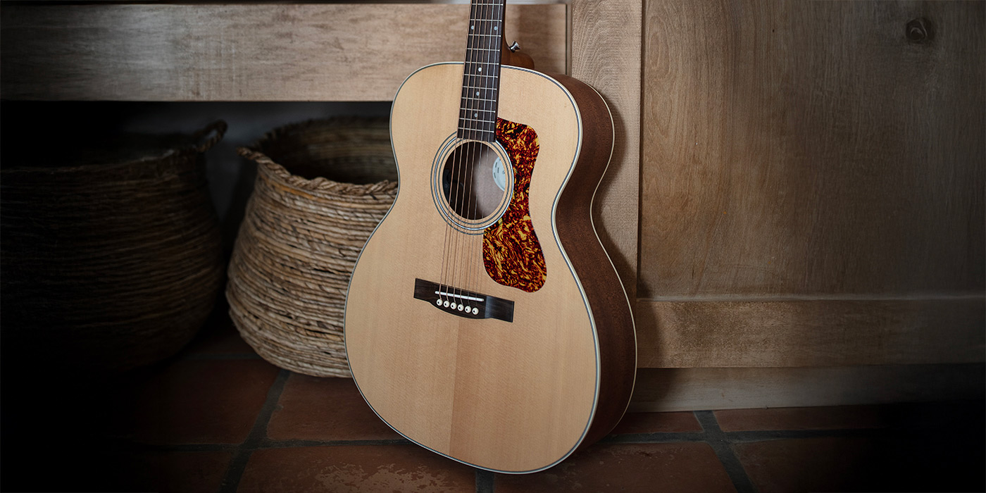 OM-240E Natural leaning against a wood chair with a record cabinet nearby