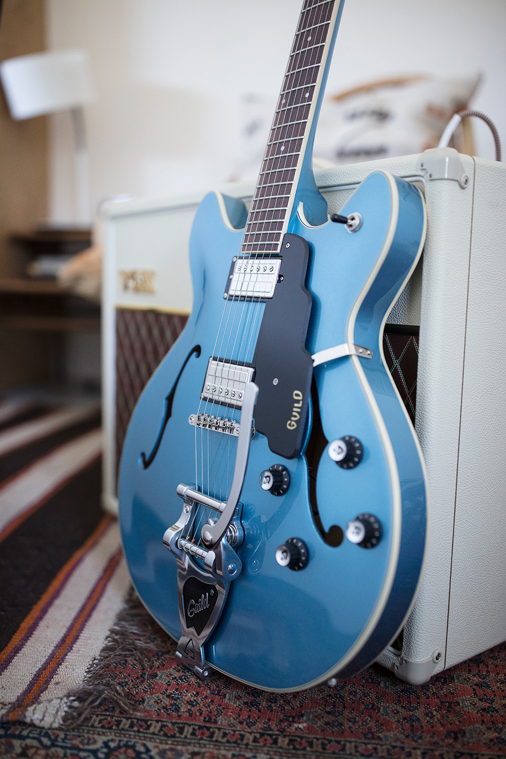 Starfire I DC Pelham Blue leaning against an amp in a cozy room