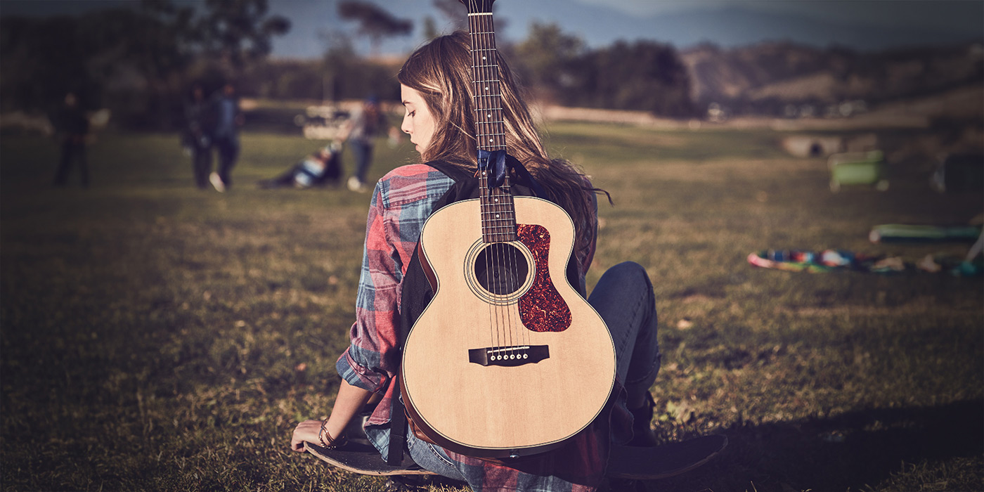 Jumbo Junior Mahogany acoustic guitar leaning against a brick wall