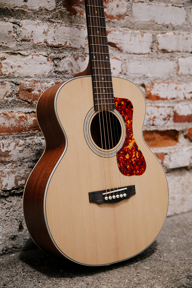 Close-up of Jumbo Junior Mahogany body in front of a brick wall