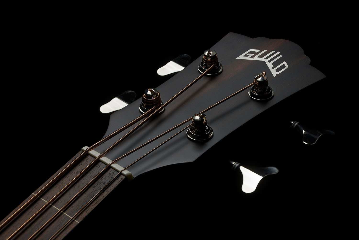 Close up of B-240E Natural Fretless guitar head showing Guild logo