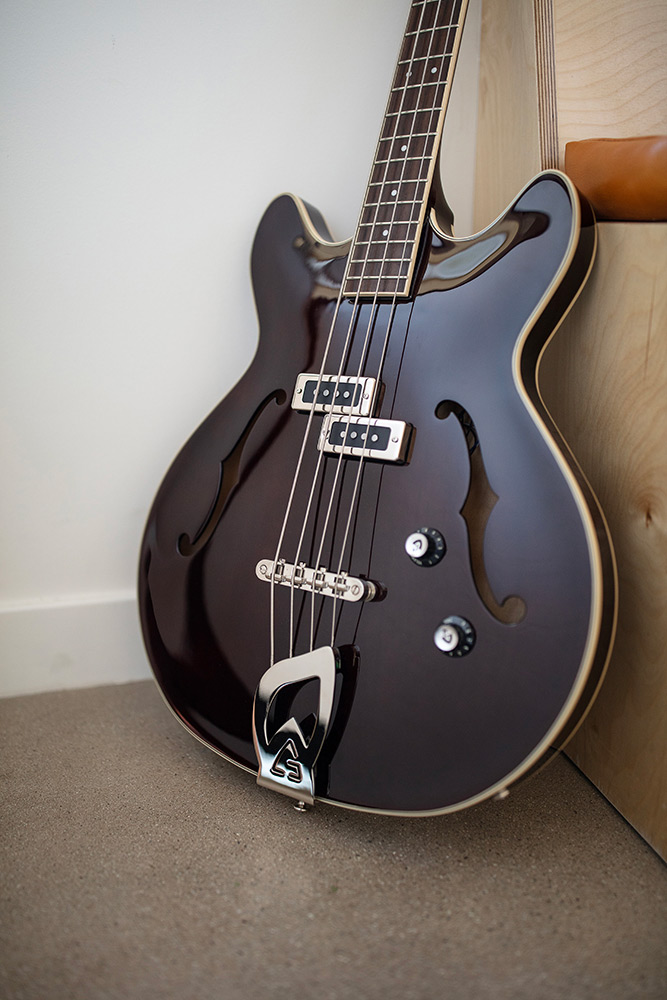 Starfire I Vintage Walnut bass body leaning against a wood bench