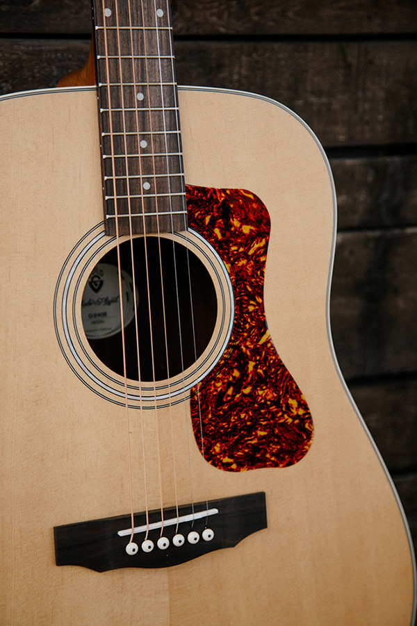 Close up D-240E Natural body showing pickguard, soundhole, bridge, and Solid Sitka Spruce top