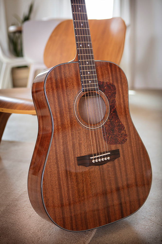 D-150 acoustic guitar leaning against a wood chair in a cozy room