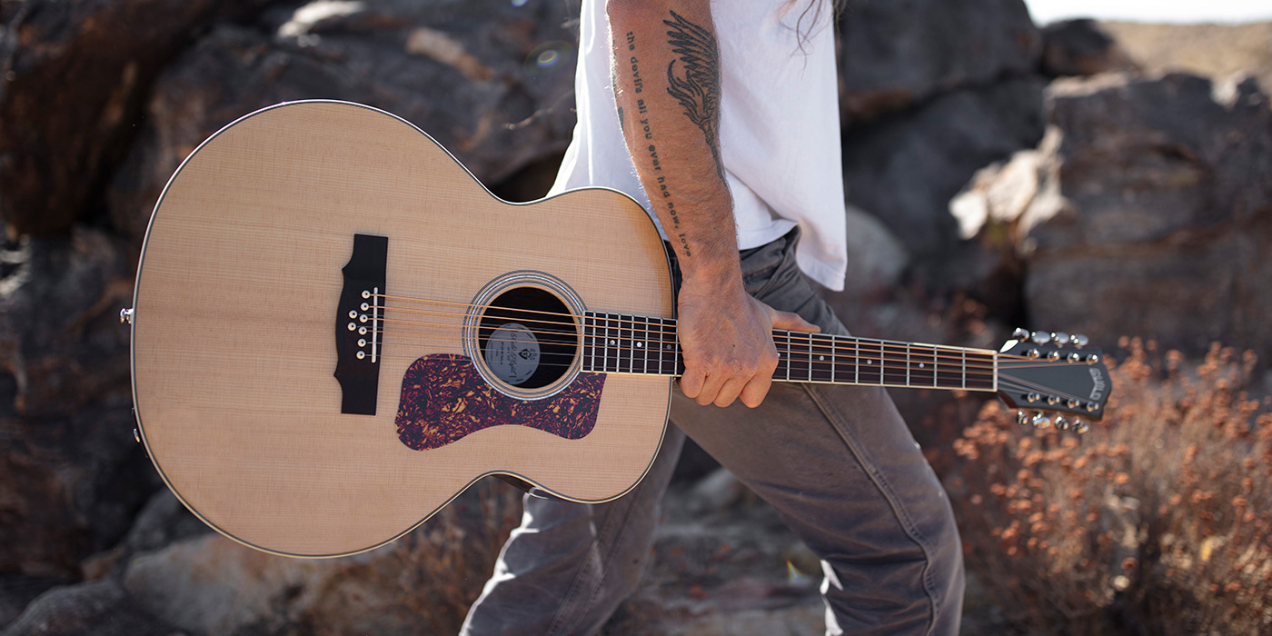 BT-258E Deluxe Baritone Natural guitar being held while a guitarist walks amongst a rocky landscape