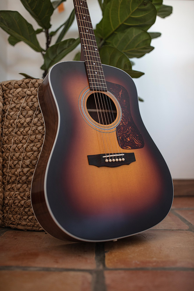 View of D-50 Standard Antique Burst leaning against a wicker pot with plant