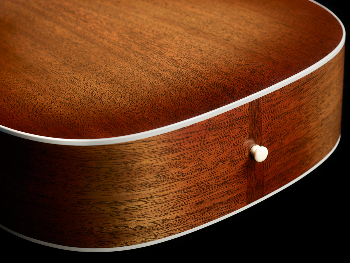 Close-up of M-40 Standard Pacific Sunset Burst white ABS body binding, solid African Mahogany back, and strap pin