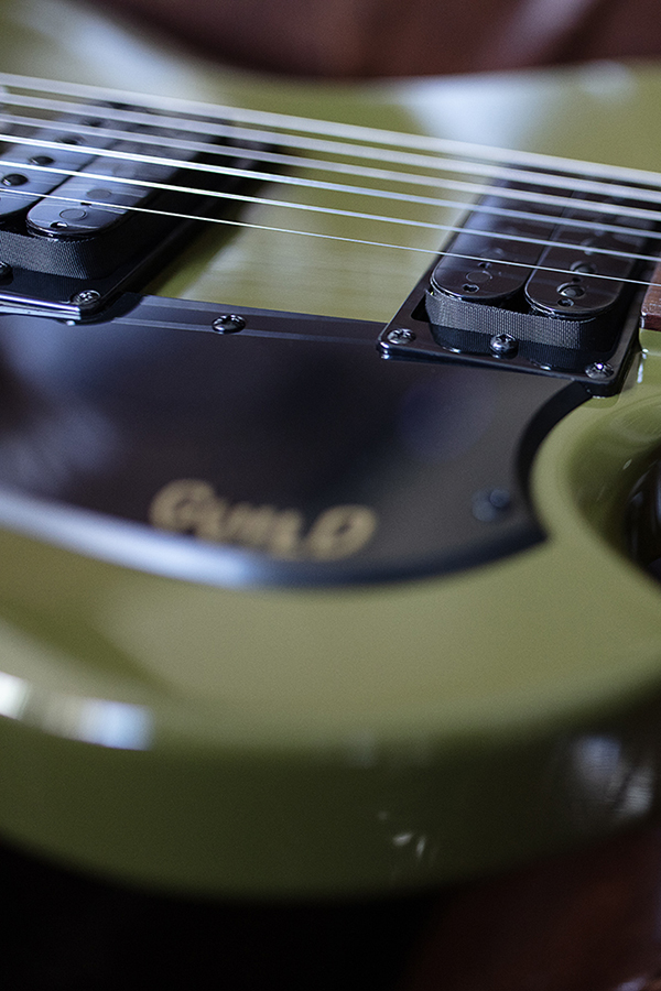 Close up of Polara Phantom Green nec, and strings with guitar laying on leather chair thumbnail