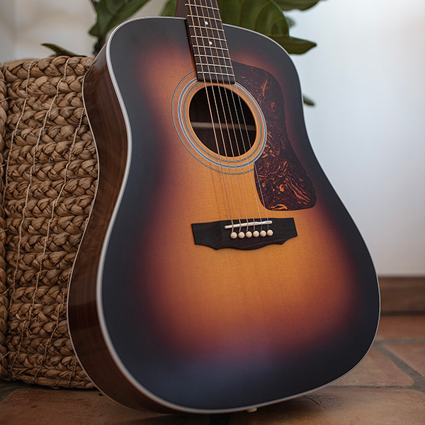 View of D-50 Standard Antique Burst leaning against a wicker pot with plant thumb