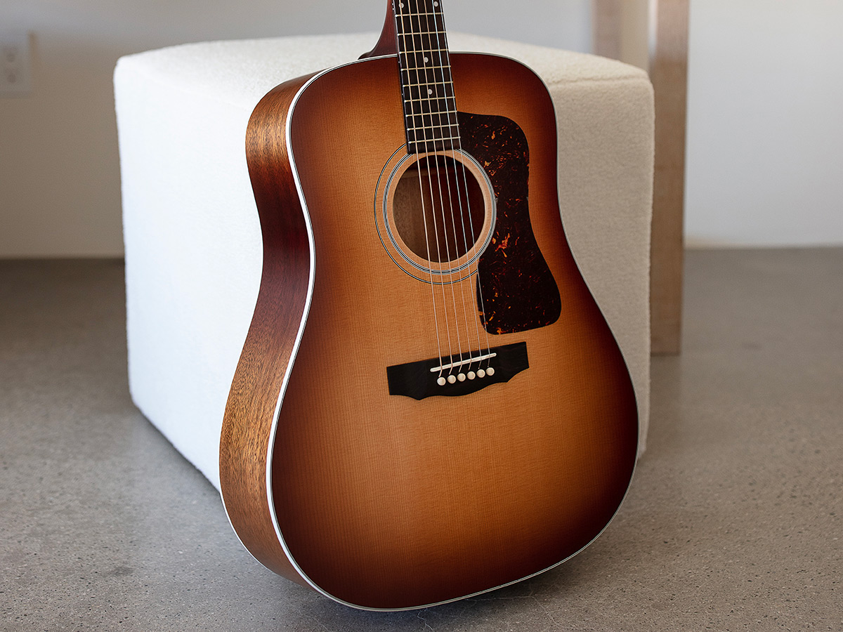 D-40 Standard Pacific Sunset Burst guitar leaning against a white ottoman
