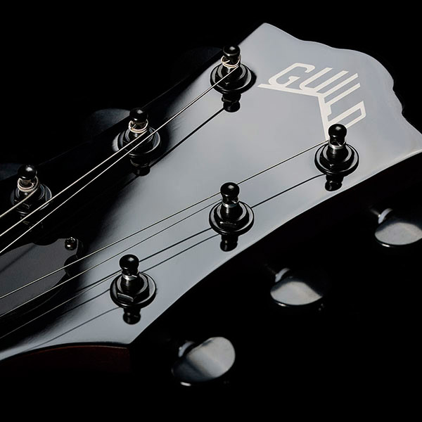 Close-up of Polara Limited Night Edition Vintage Walnut headstock with Guild Peak logo thumb