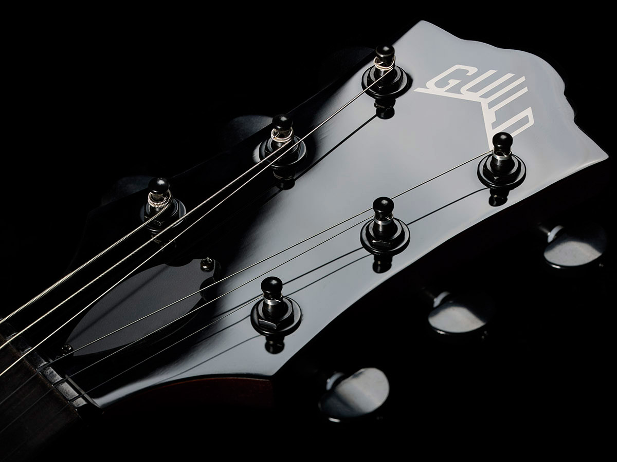 Close-up of Polara Limited Night Edition Vintage Walnut headstock with Guild Peak logo.