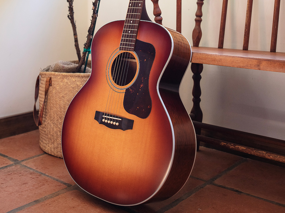 F-40 Standard Pacific Sunset Burst guitar leaning against a wood bench indoors
