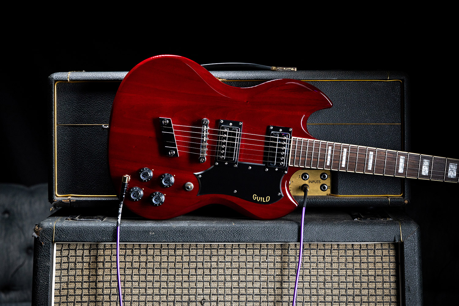 Polara Deluxe Cherry Red laying horizontal on top of a guitar amp