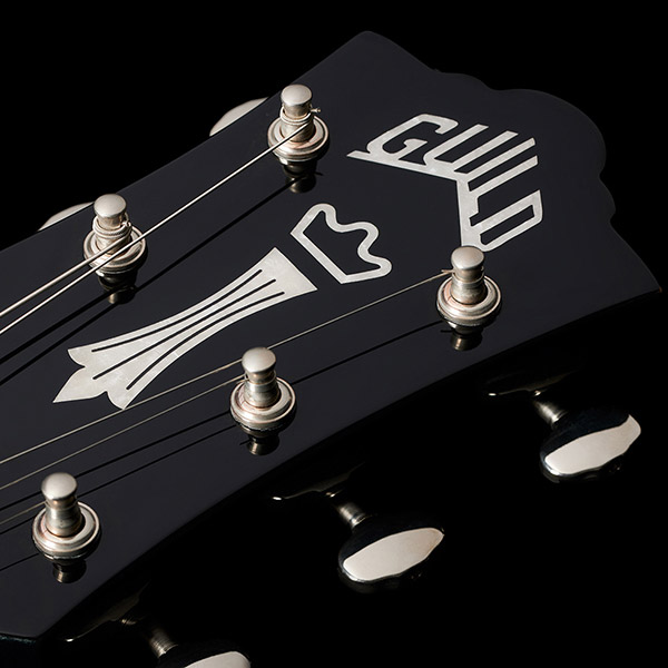 Close-up of the Polara Deluxe Kingswood Green headstock featuring Guild Peak logo thumb