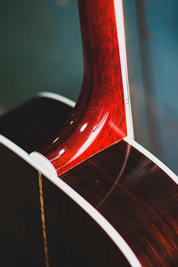 Close-up of F-512 guitar's neck joint, showcasing polished wood grain and white binding details.