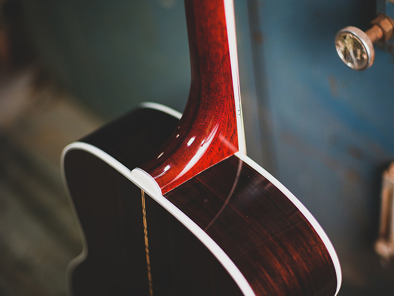Close-up of F-512 guitar's neck joint, showcasing polished wood grain and white binding details.