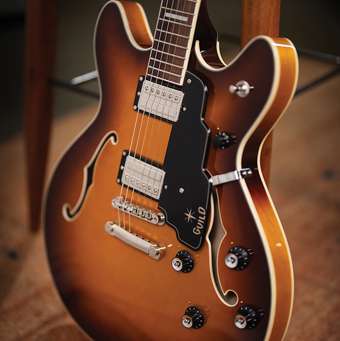 Close-up of the neck and body on a Starfire Deluxe DC Sweet Tea, showing the pickguard with Guild logo, both pickups, tailpiece, and control knobs.