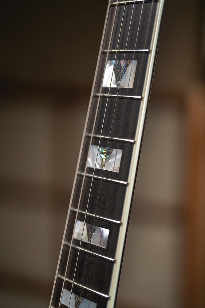 Close-up looking down the bound ebony fingerboard on a Starfire Custom DC GVT GH, showing the mother-of-pearl V-block inlays.