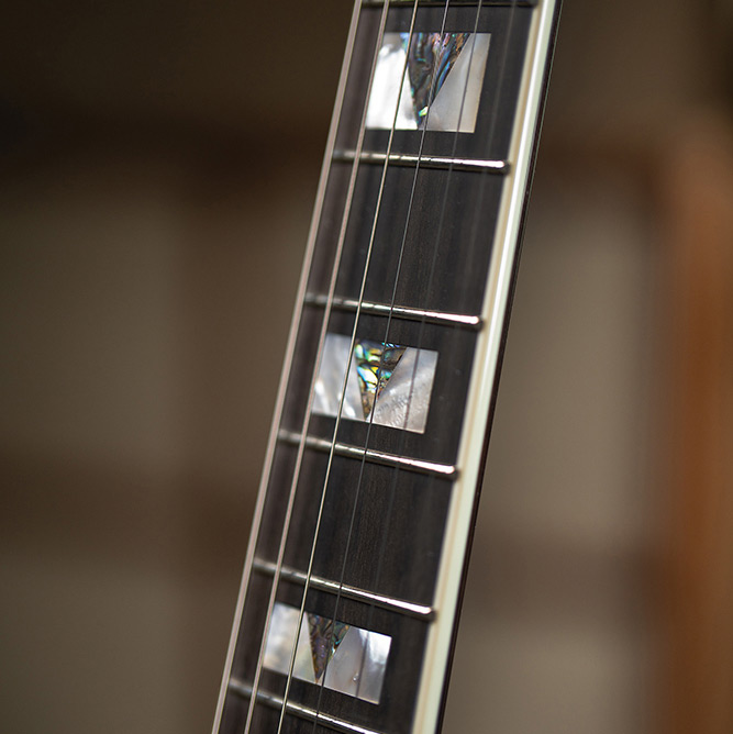 Close-up looking down the bound ebony fingerboard on a Starfire Custom DC GVT GH, showing the mother-of-pearl V-block inlays.