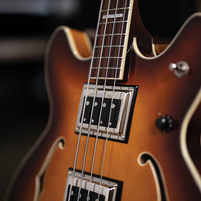 Close-up of the neck meeting the body on a Starfire Deluxe Bass Sweet Tea, showing the BS-1 BiSonic pickups and rosewood fingerboard with block inlays.