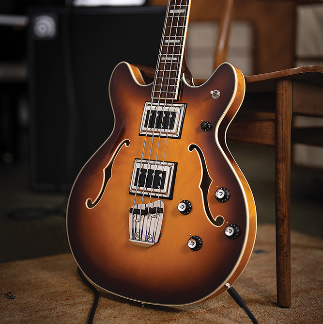 Angled full view of a Starfire Deluxe Bass Sweet Tea leaning on a chair, showing the double-cutaway body and pickups.