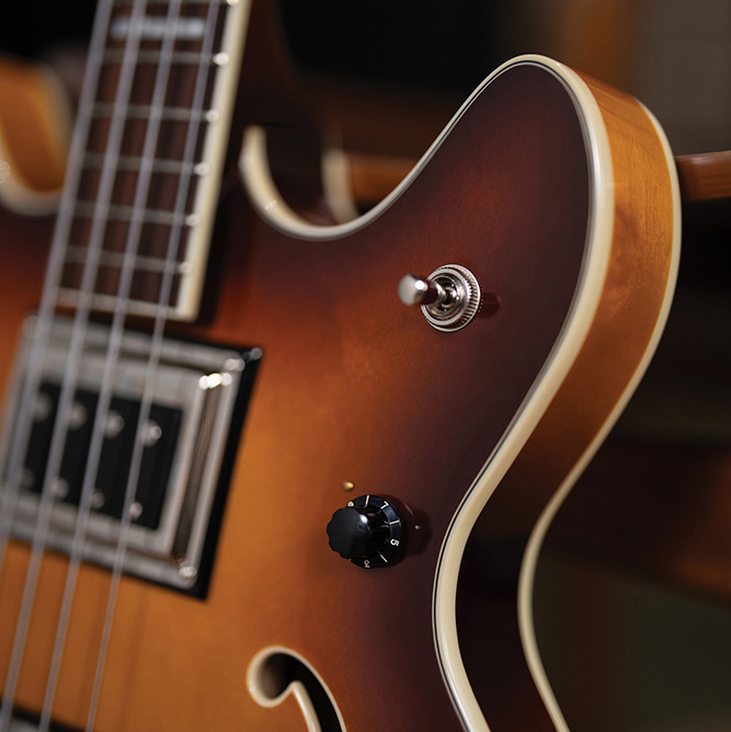 Close-up of the upper cutaway on a Starfire Deluxe Bass Sweet Tea, showing the pickup selector switch, control knob, and fingerboard inlay.