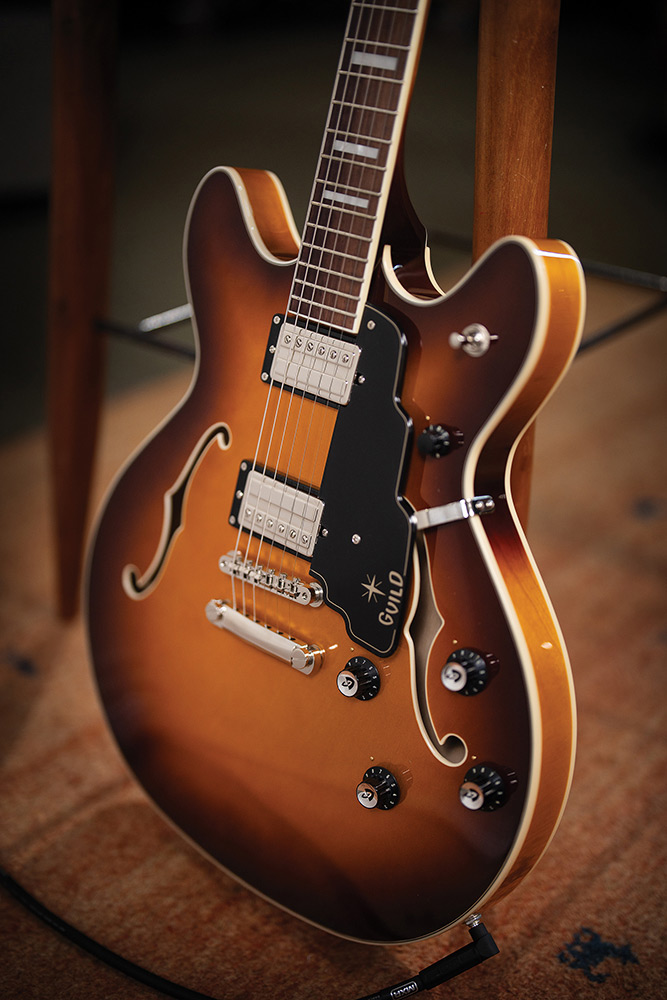 Close-up of the neck and body on a Starfire Deluxe DC Sweet Tea, showing the pickguard with Guild logo, both pickups, tailpiece, and control knobs.