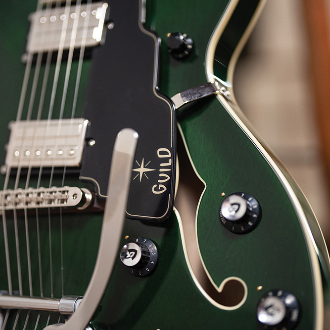 Close-up of the Starfire Deluxe DC GVT Emerald Green, showing the Guild Vibrato tailpiece, both HB-2+ pickups, and pickguard.
