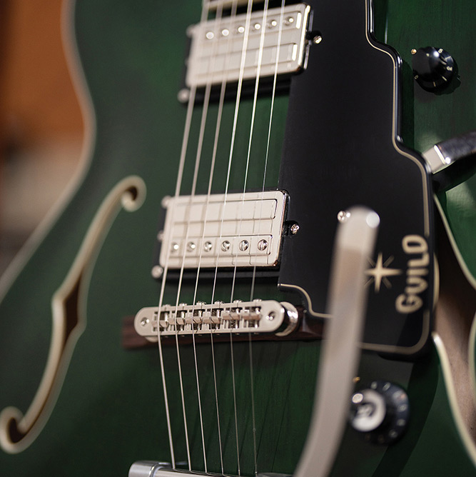 Close-up of a Starfire Deluxe DC GVT Emerald Green, showing both HB-2+ pickups, pickguard, and the Guild Vibrato tailpiece arm.