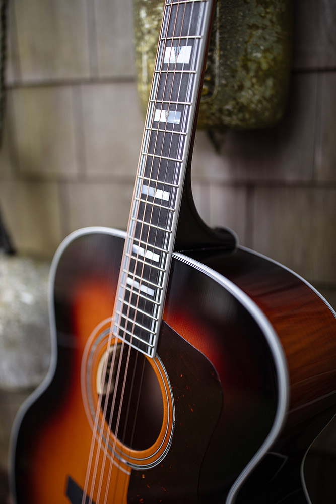Close-up of F-55E Maple acoustic guitar's neck and body, showcasing its wood grain and fretboard details.