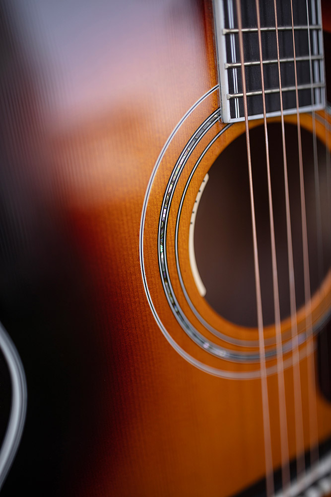 Close-up of F-55E Maple acoustic guitar, highlighting the soundhole, strings, and intricate wood grain.
