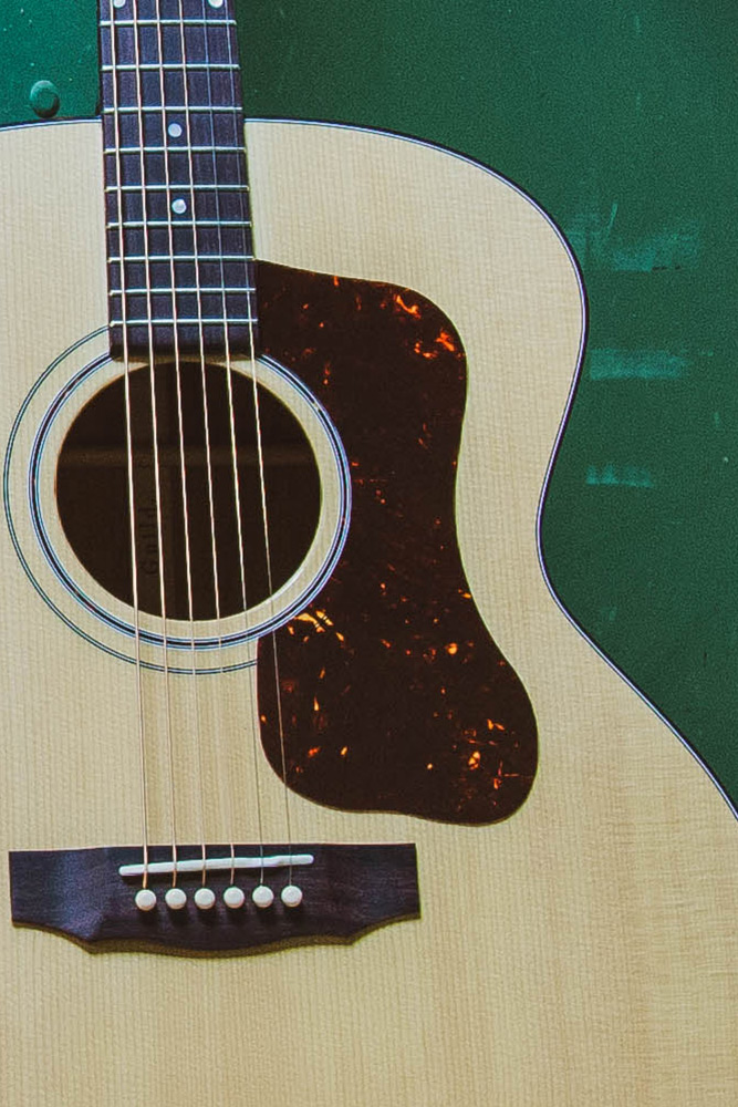 Body of F-40 acoustic guitar featuring a Natural wood body, tortoiseshell pickguard, and six strings against a green background.
