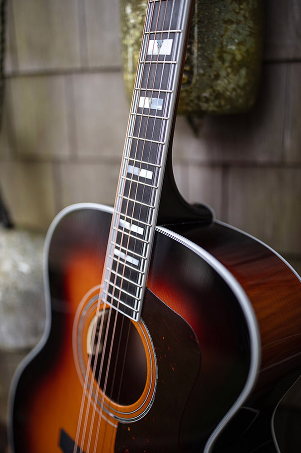Close-up of F-55E Maple acoustic guitar's neck and body, showcasing its wood grain and fretboard details.