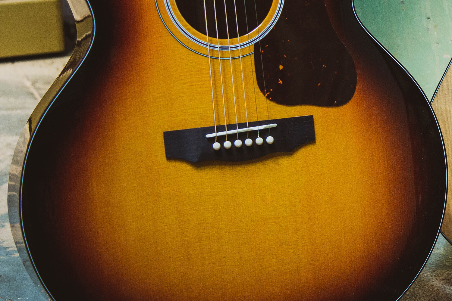Close-up of F-40 acoustic guitar's body, showcasing the strings, bridge, and a warm, antique burst finish.