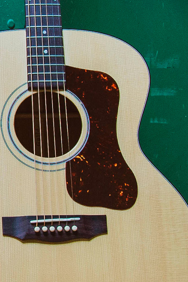 Body of F-40 acoustic guitar featuring a Natural wood body, tortoiseshell pickguard, and six strings against a green background.