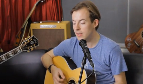 Jack Steadman playing guitar and singing during a performance.