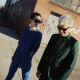 David Byrne and St. Vincent walking down a street past a building with graffiti